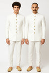 Two men in coordinated white Jodhpuri suits with gold-tone buttons for an Indian family wedding in Paris