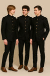 Three men wearing coordinated black Jodhpuri suits with gold-tone buttons for a Mumbai wedding